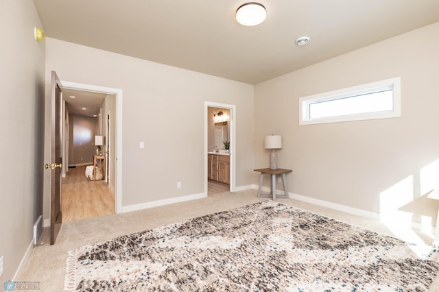 carpeted bedroom featuring ensuite bathroom and baseboards