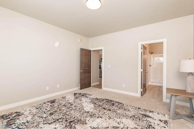 bedroom featuring ensuite bath, stainless steel refrigerator with ice dispenser, carpet flooring, and baseboards