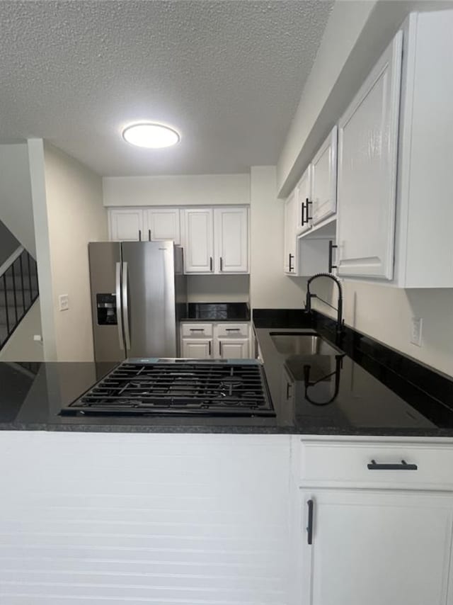 kitchen featuring a sink, dark countertops, white cabinetry, a peninsula, and stainless steel fridge with ice dispenser