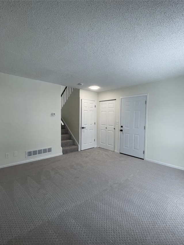 interior space with stairway, baseboards, a textured ceiling, and visible vents