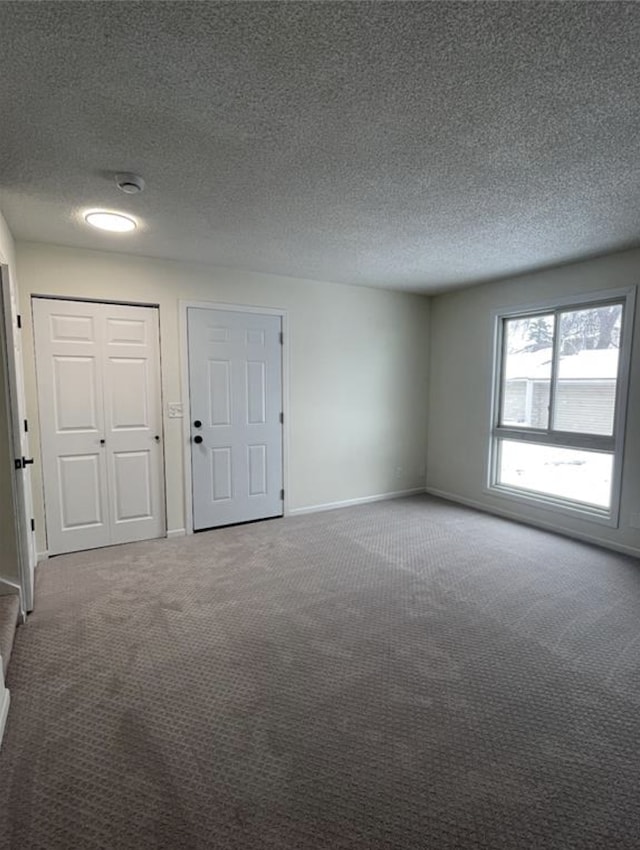 unfurnished room featuring a textured ceiling, baseboards, and carpet