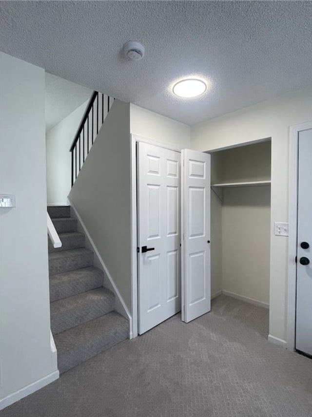 interior space with carpet flooring, a textured ceiling, and baseboards