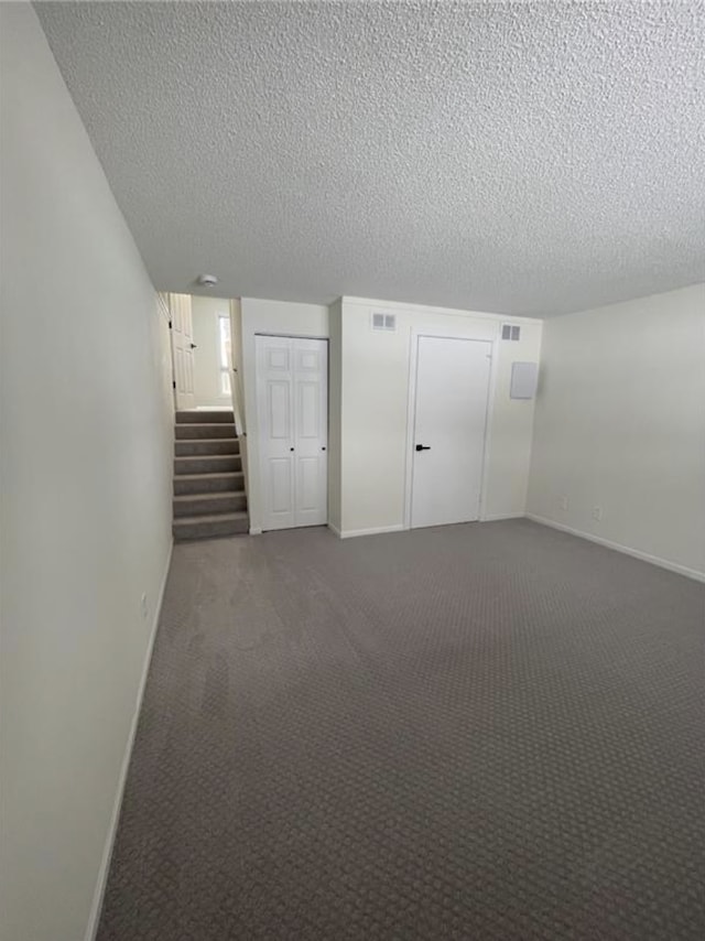 empty room with stairs, baseboards, and dark carpet