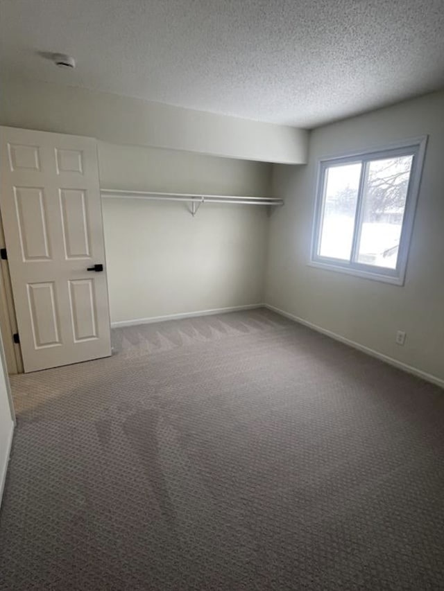 unfurnished bedroom with carpet, baseboards, and a textured ceiling