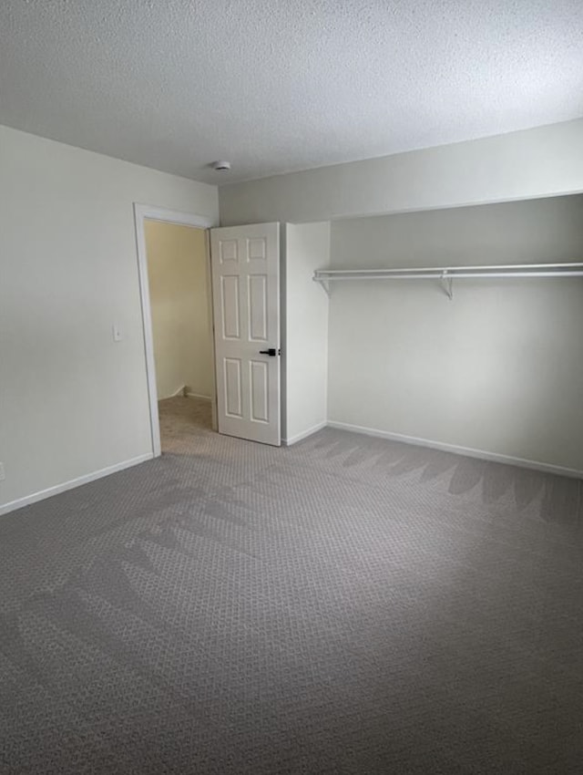 unfurnished bedroom with carpet flooring, a textured ceiling, and baseboards