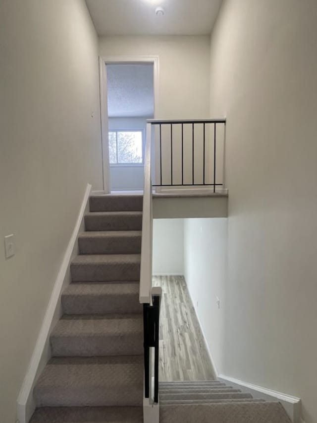 stairway featuring baseboards and wood finished floors