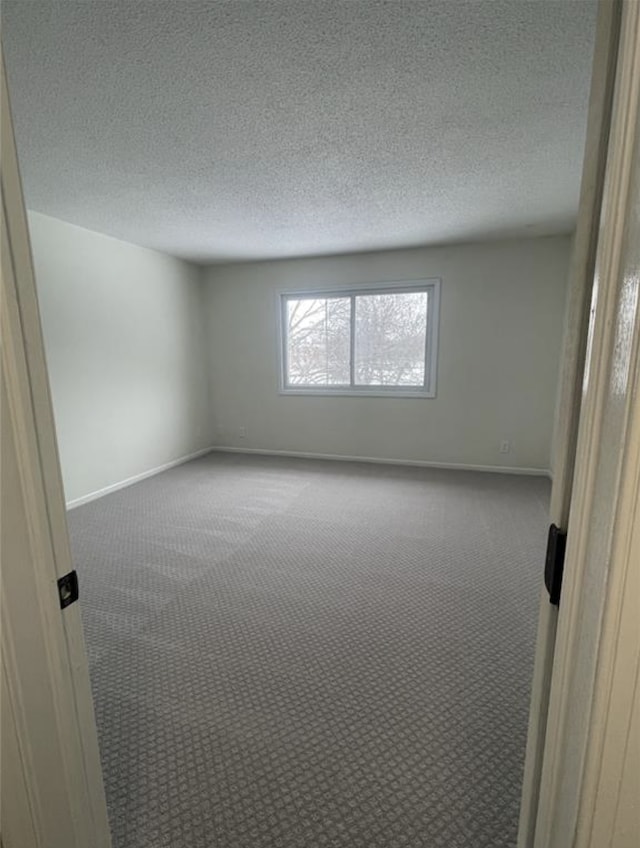 empty room featuring baseboards, a textured ceiling, and carpet flooring