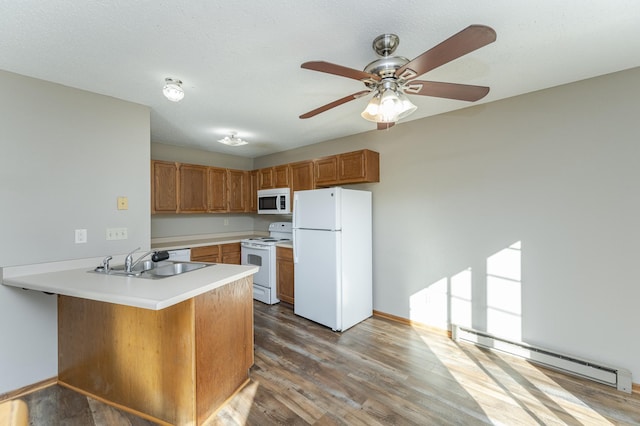 kitchen with white appliances, a baseboard radiator, a sink, and wood finished floors