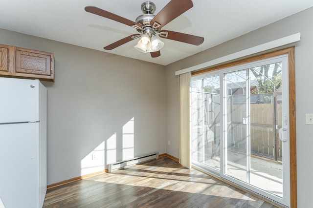 spare room featuring a baseboard heating unit, baseboards, and wood finished floors