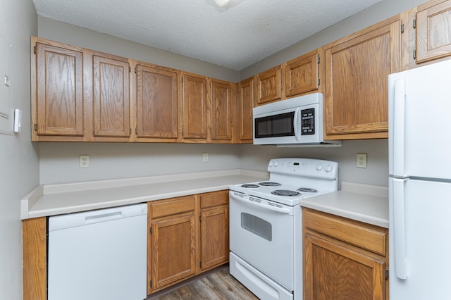 kitchen with light wood-type flooring, white appliances, light countertops, and a textured ceiling