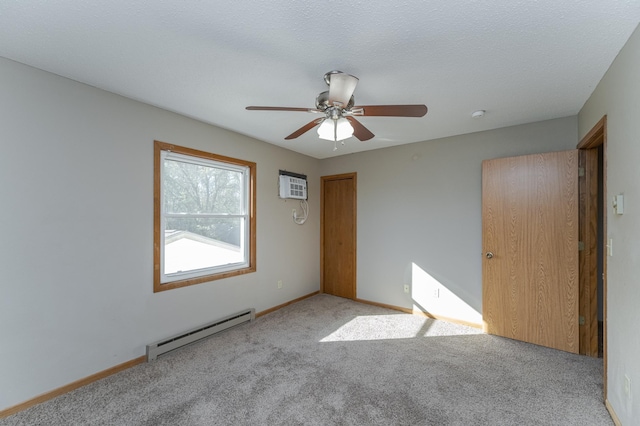 unfurnished bedroom featuring a textured ceiling, a baseboard heating unit, carpet flooring, baseboards, and a wall mounted AC