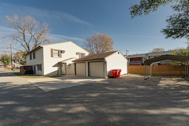 view of side of home featuring an outdoor structure, a detached garage, and fence