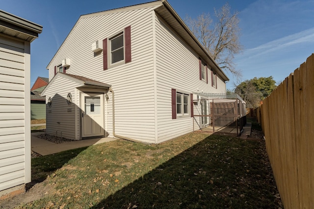 back of house featuring an outbuilding, a fenced backyard, and a lawn