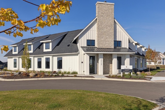 exterior space with a chimney, a shingled roof, board and batten siding, a standing seam roof, and metal roof