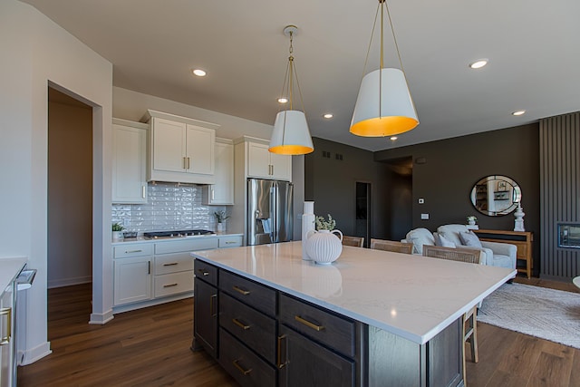 kitchen with open floor plan, a breakfast bar area, stainless steel fridge, white cabinetry, and gas cooktop