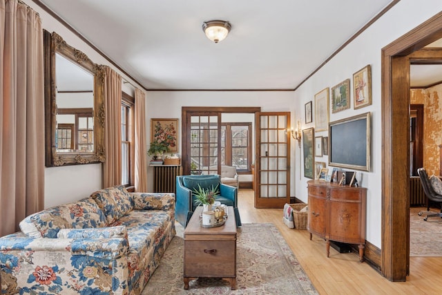 living room with ornamental molding, french doors, light wood-style flooring, and baseboards