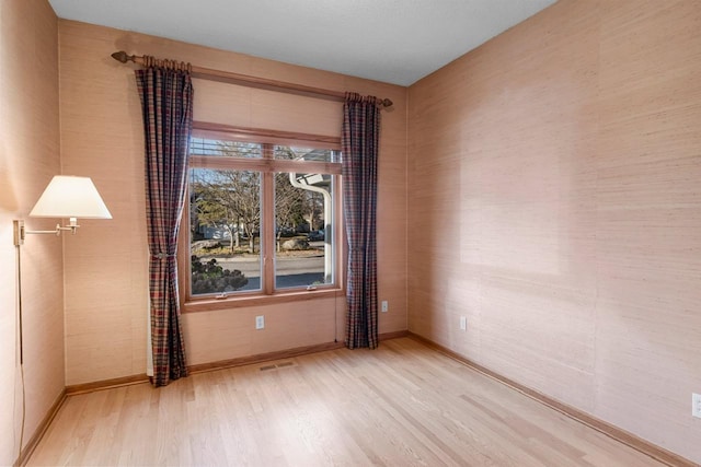 unfurnished room with baseboards, visible vents, and light wood-style floors