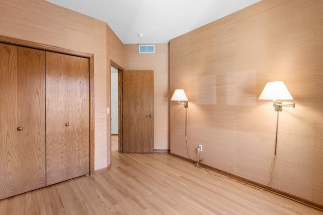 unfurnished bedroom featuring a closet, visible vents, baseboards, and light wood finished floors