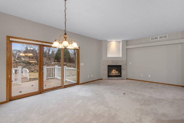 unfurnished living room featuring baseboards, visible vents, a tiled fireplace, carpet, and a chandelier