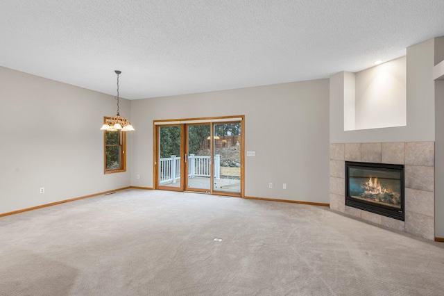 unfurnished living room featuring carpet, a textured ceiling, a tiled fireplace, and baseboards