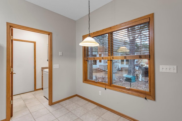 unfurnished dining area featuring washer / clothes dryer, light tile patterned flooring, and baseboards