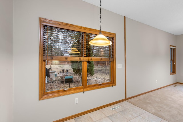 unfurnished dining area with carpet, visible vents, baseboards, and tile patterned floors