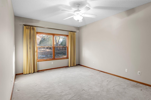 spare room featuring a textured ceiling, carpet floors, visible vents, and baseboards