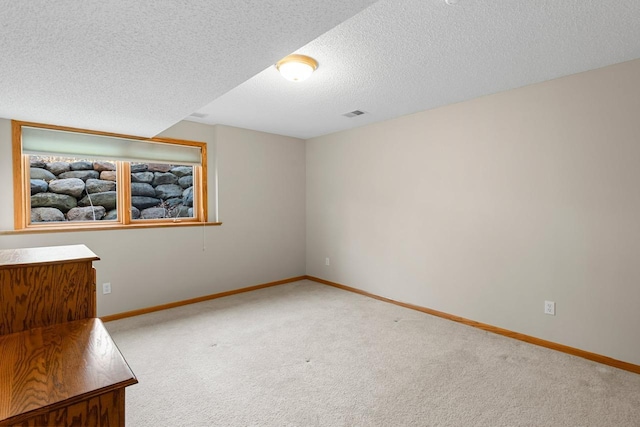 carpeted spare room featuring a textured ceiling, visible vents, and baseboards