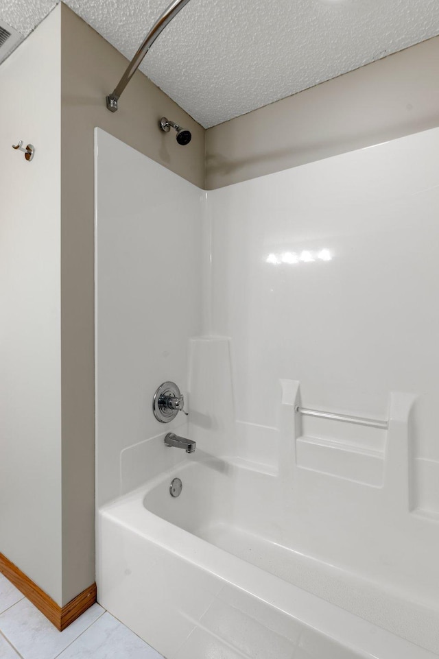 bathroom featuring baseboards, tub / shower combination, and a textured ceiling