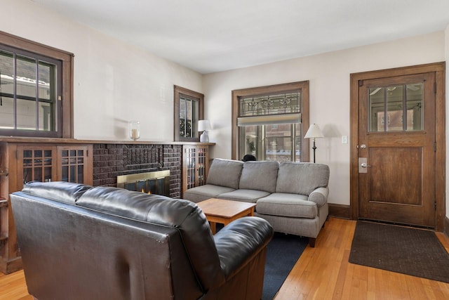 living room with baseboards, light wood-style floors, and a brick fireplace