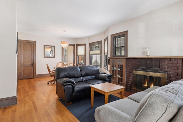 living room with a brick fireplace, baseboards, and light wood finished floors