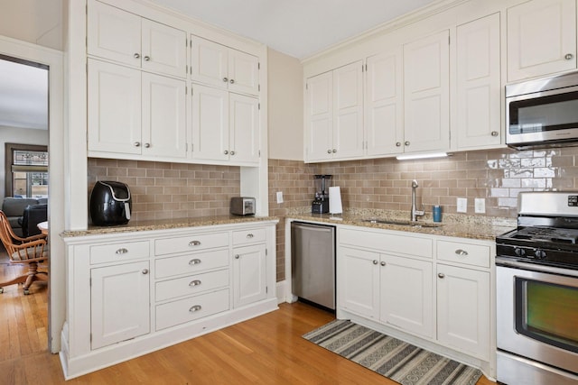 kitchen with a sink, white cabinetry, light wood finished floors, and stainless steel appliances