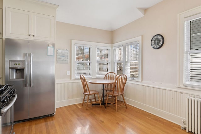 dining space with a wainscoted wall, radiator, and light wood-style flooring