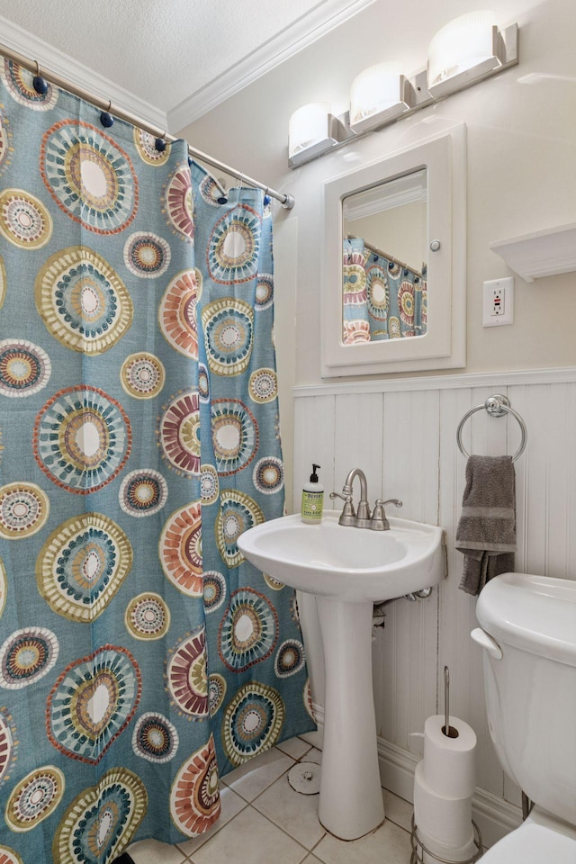 full bathroom featuring tile patterned floors, a shower with curtain, toilet, a textured ceiling, and crown molding