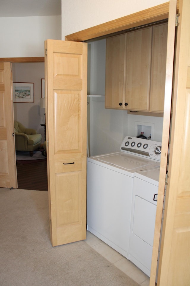 washroom with washing machine and clothes dryer, cabinet space, and light carpet