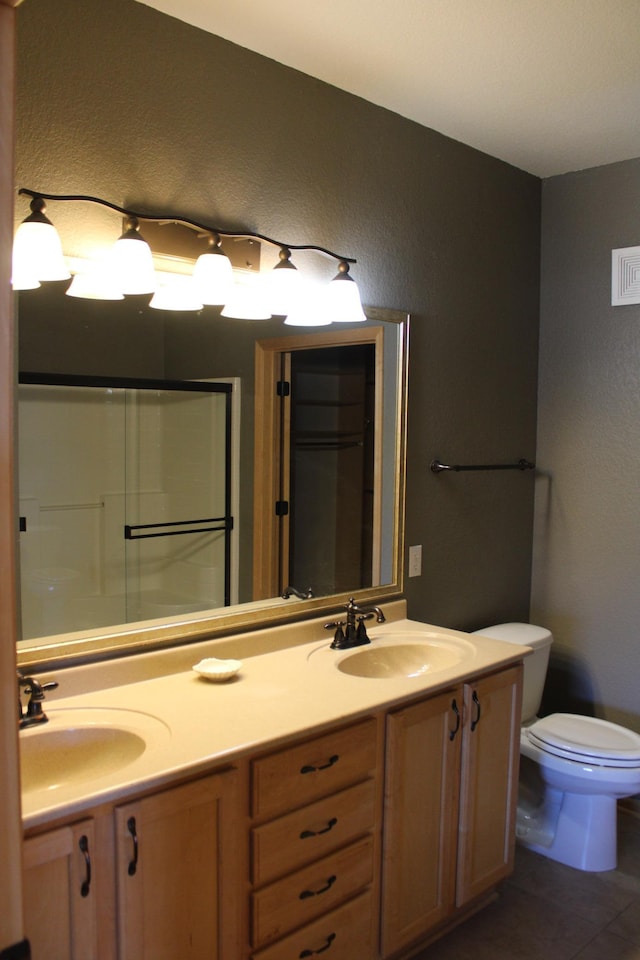 bathroom with double vanity, tile patterned flooring, toilet, and a sink