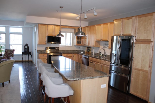 kitchen featuring dark wood-type flooring, light brown cabinets, a sink, a kitchen island, and stainless steel appliances