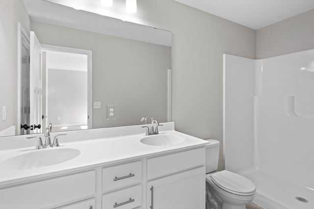 full bathroom featuring toilet, double vanity, a sink, and walk in shower