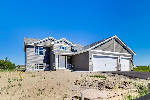 view of front of house featuring an attached garage, aphalt driveway, and stone siding