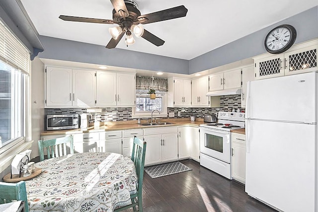 kitchen with white cabinetry, white appliances, under cabinet range hood, and a sink