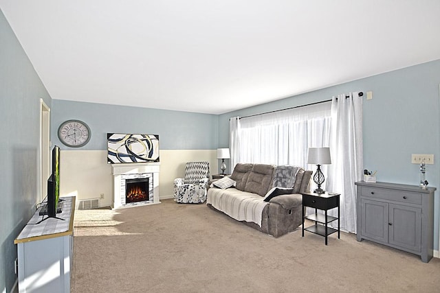 living room with light colored carpet, visible vents, and a lit fireplace