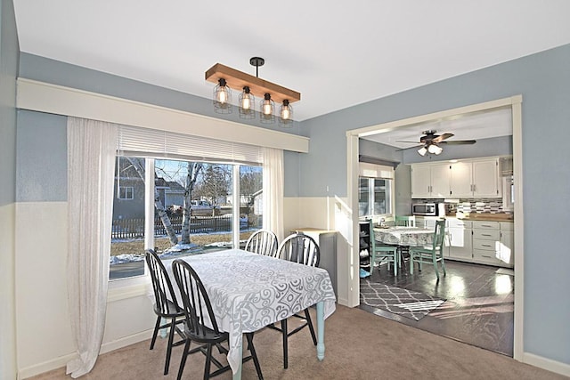 carpeted dining space featuring baseboards and ceiling fan