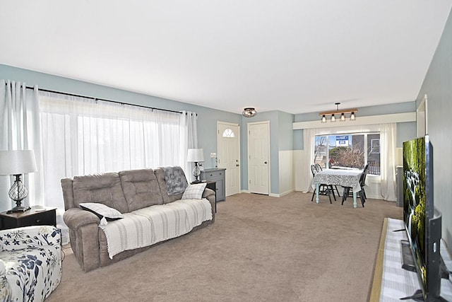 living room featuring light colored carpet, baseboards, and a chandelier