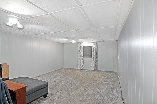 sitting room with carpet flooring, wood walls, and a drop ceiling