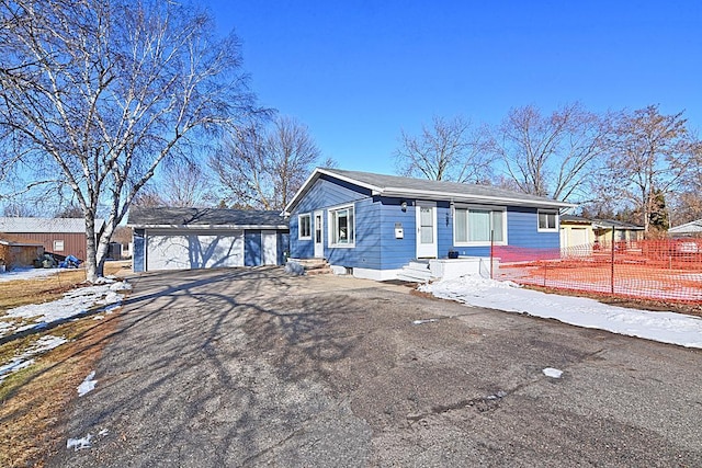 ranch-style home featuring an outbuilding, driveway, entry steps, fence, and a garage