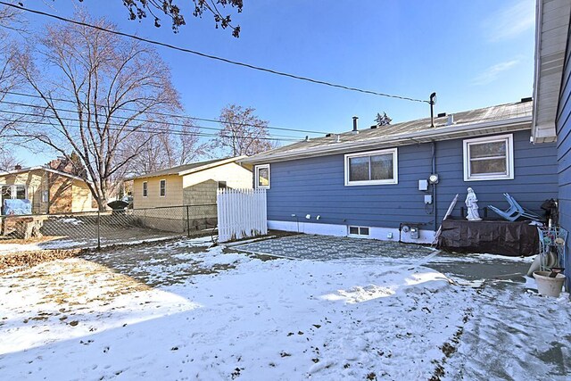 snow covered rear of property with fence