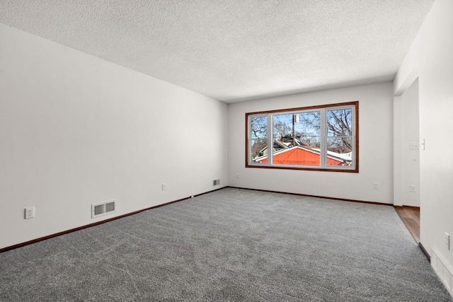 spare room with visible vents, baseboards, a textured ceiling, and carpet flooring