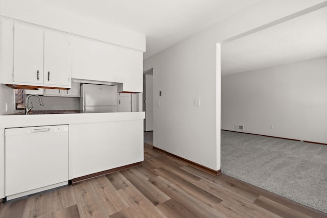 kitchen featuring visible vents, wood finished floors, freestanding refrigerator, white cabinets, and white dishwasher