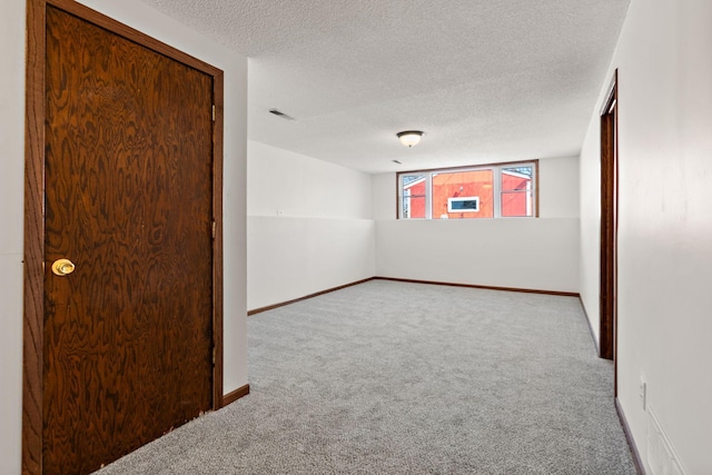 unfurnished room with carpet flooring, visible vents, baseboards, and a textured ceiling