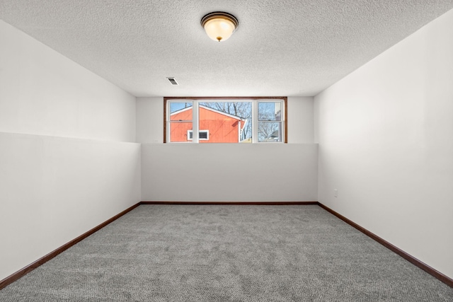 spare room featuring visible vents, a textured ceiling, baseboards, and carpet